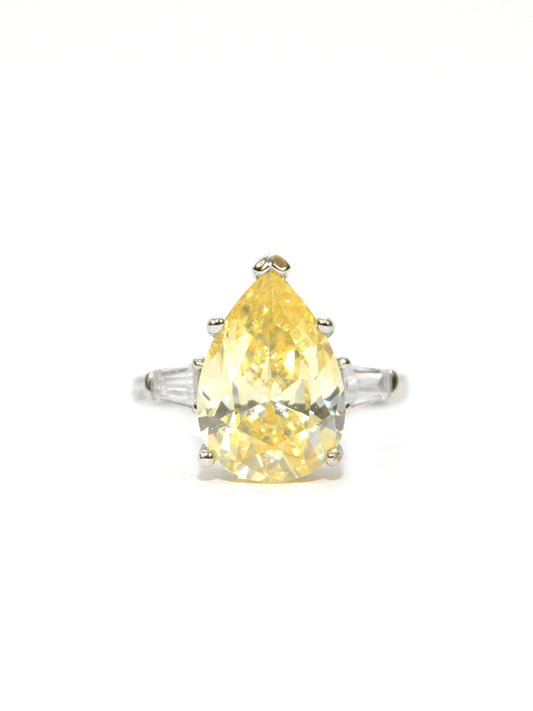 Large sparkling synthetic pear shaped yellow diamond with small rectangle baguette stones on each side set in silver alloy.